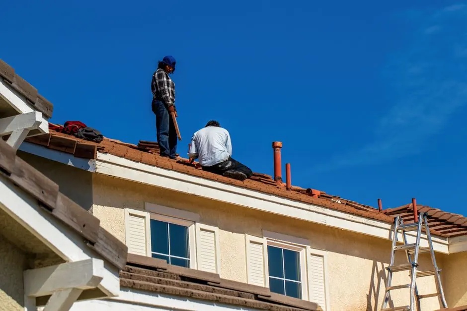 Roofers repairing clay tile on a house roof.